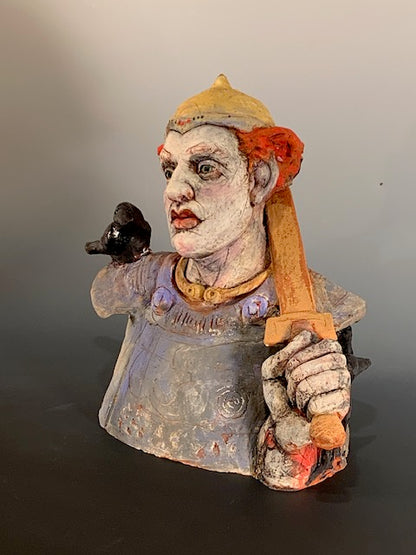 Ceramic bust with colorful face and clothing on a plain background