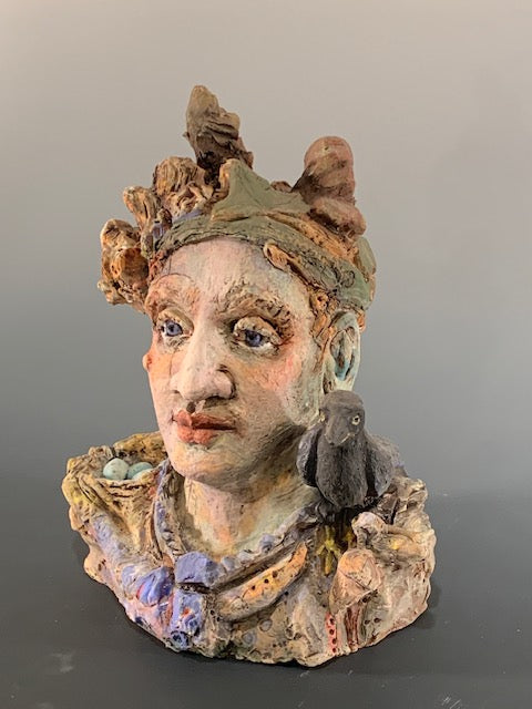 Decorative ceramic head with intricate details on a plain background