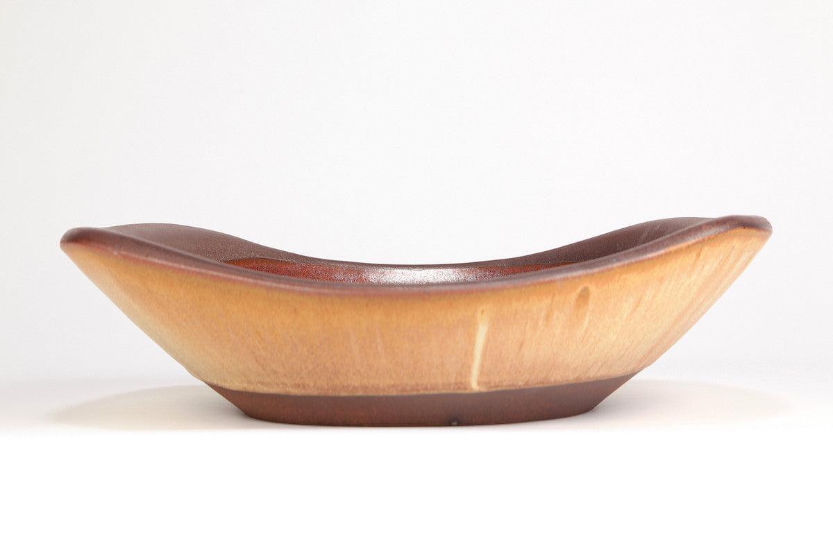 Golden ceramic bowl with a curved design on a white background