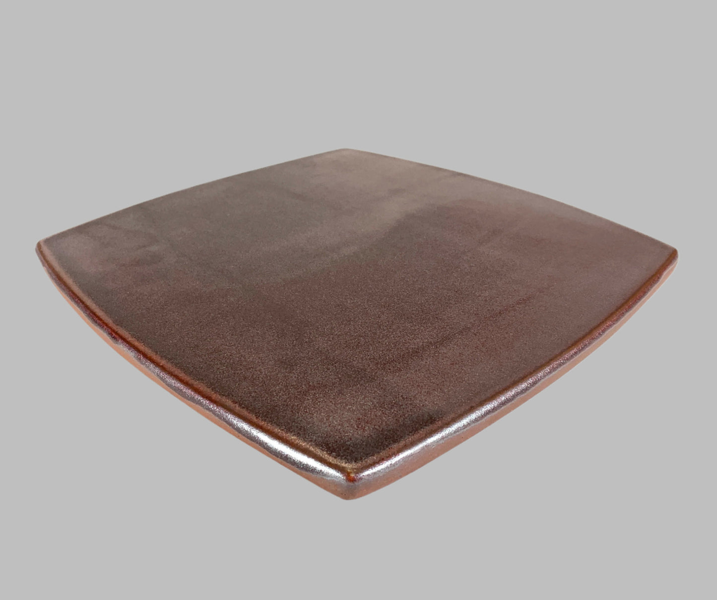 Brown ceramic pizza stone on a gray background