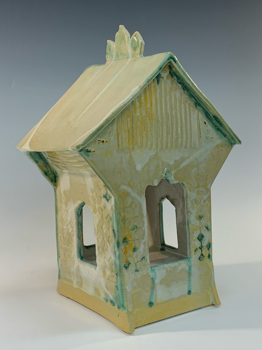 Ceramic house-shaped object with a textured surface on a gray background