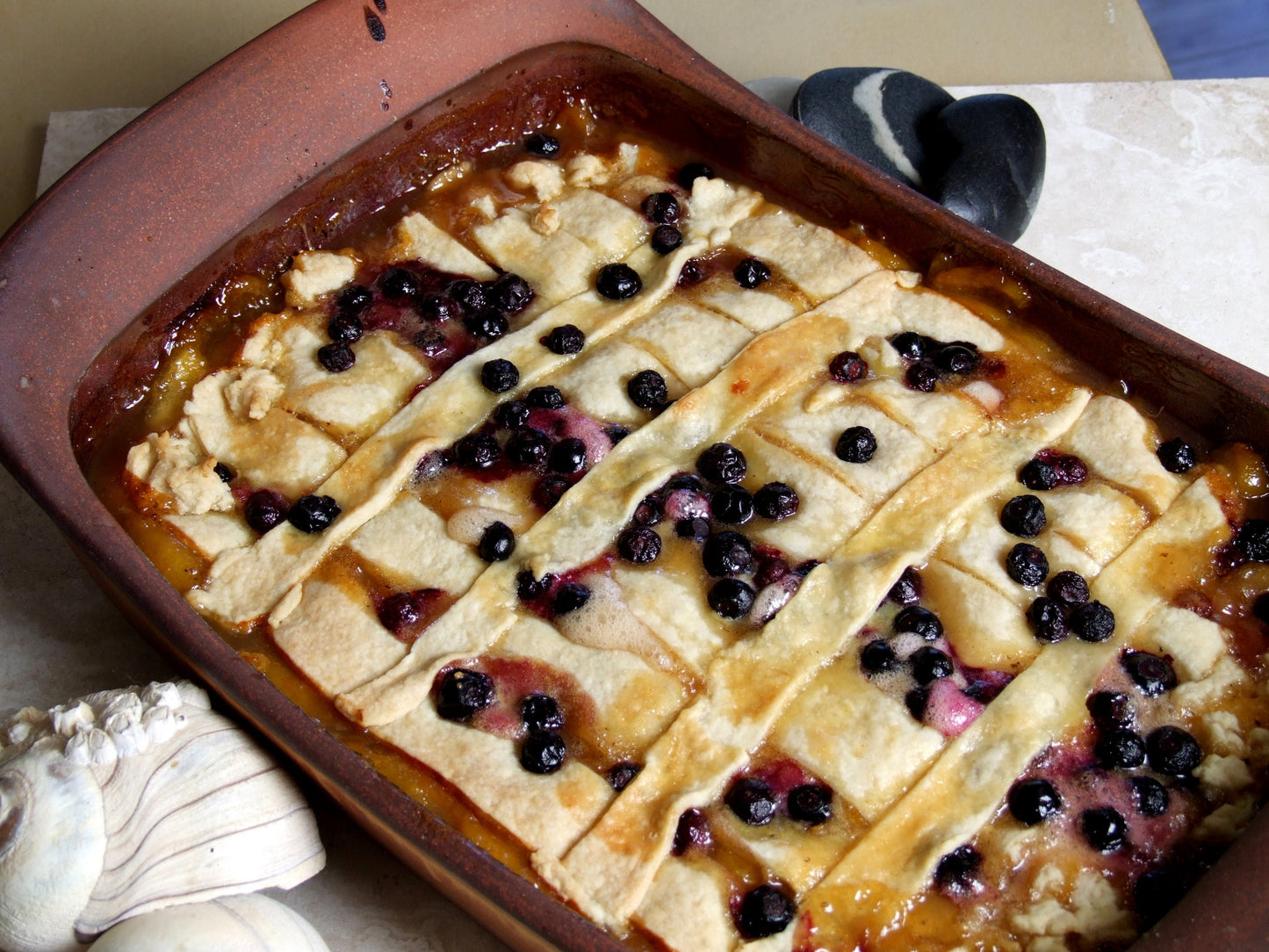 Baked dish with lattice topping and blueberries in a ceramic dish.