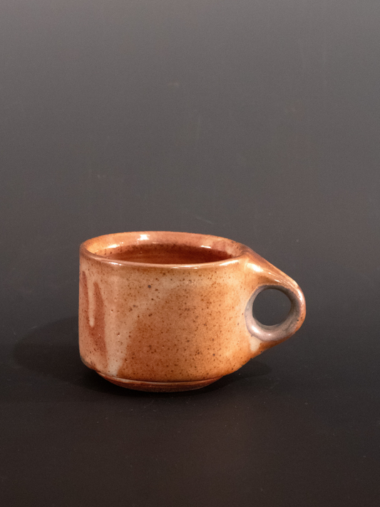 Brown ceramic mug with a handle on a black background