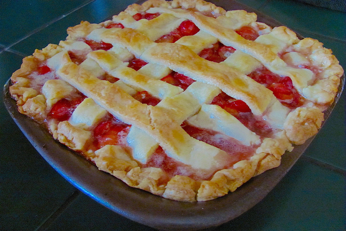 Strawberry pie with a lattice crust on a ceramic plate.