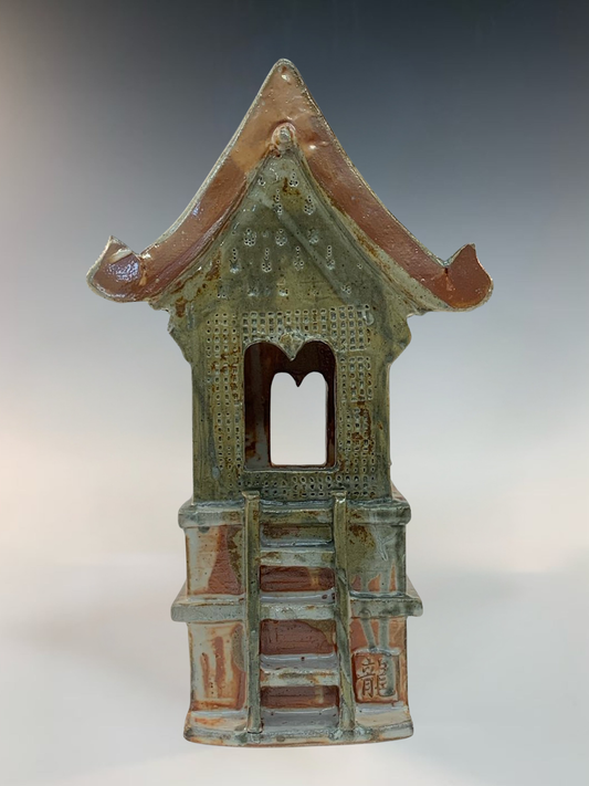 Small ceramic building with a tiled roof on a gray background