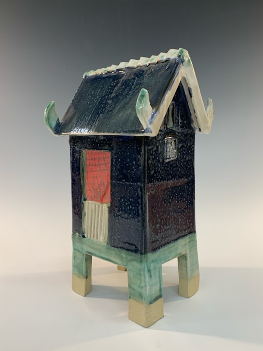 Ceramic model of a traditional building with a green base and black body on a gray background