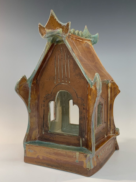 Ceramic model of a small building with a pointed roof on a gray background