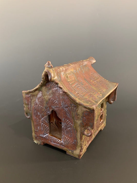 Small ceramic model of a traditional building with a tiled roof on a gray background