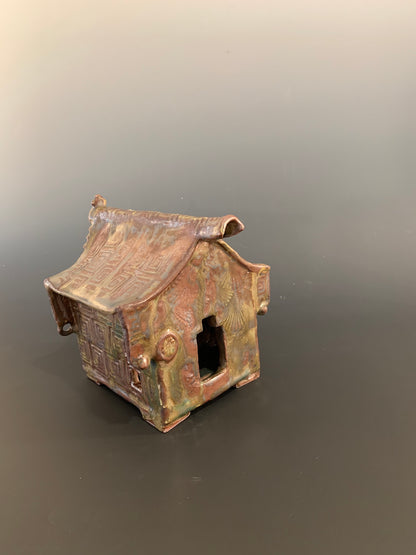 Small model of a traditional house with a tiled roof on a gray background