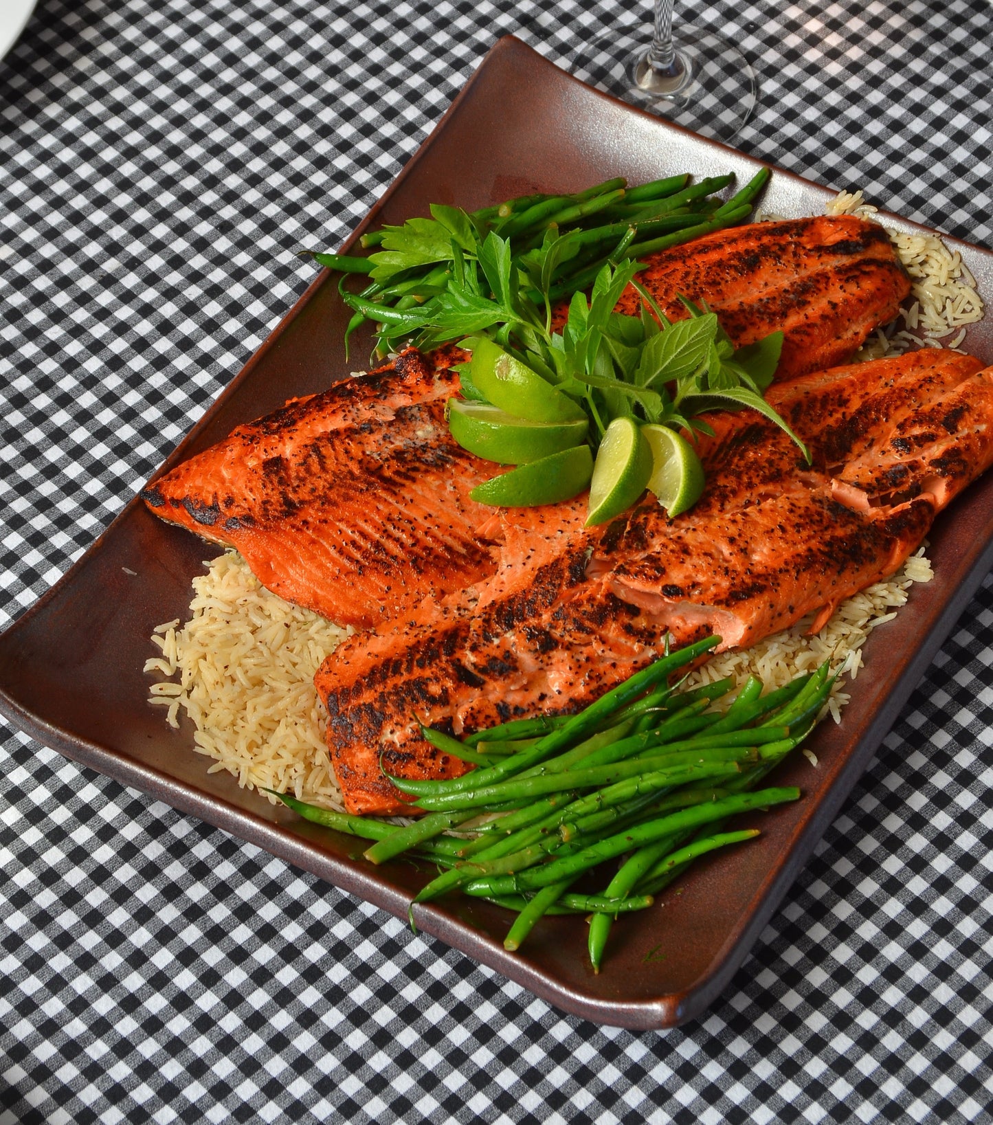 Plated dish of grilled salmon with green beans on a checkered tablecloth
